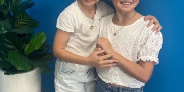 Two young girls who are participating in group therapy at QPAH hugging.