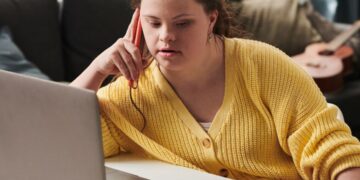 Lady with Downs syndrome concentrating on new NDIS funding plans on her laptop.