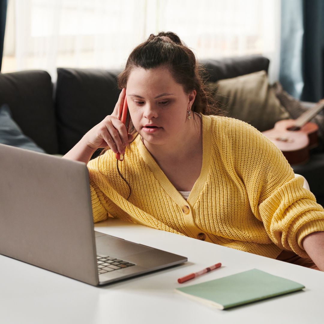 Lady with Downs syndrome concentrating on new NDIS funding plans on her laptop.