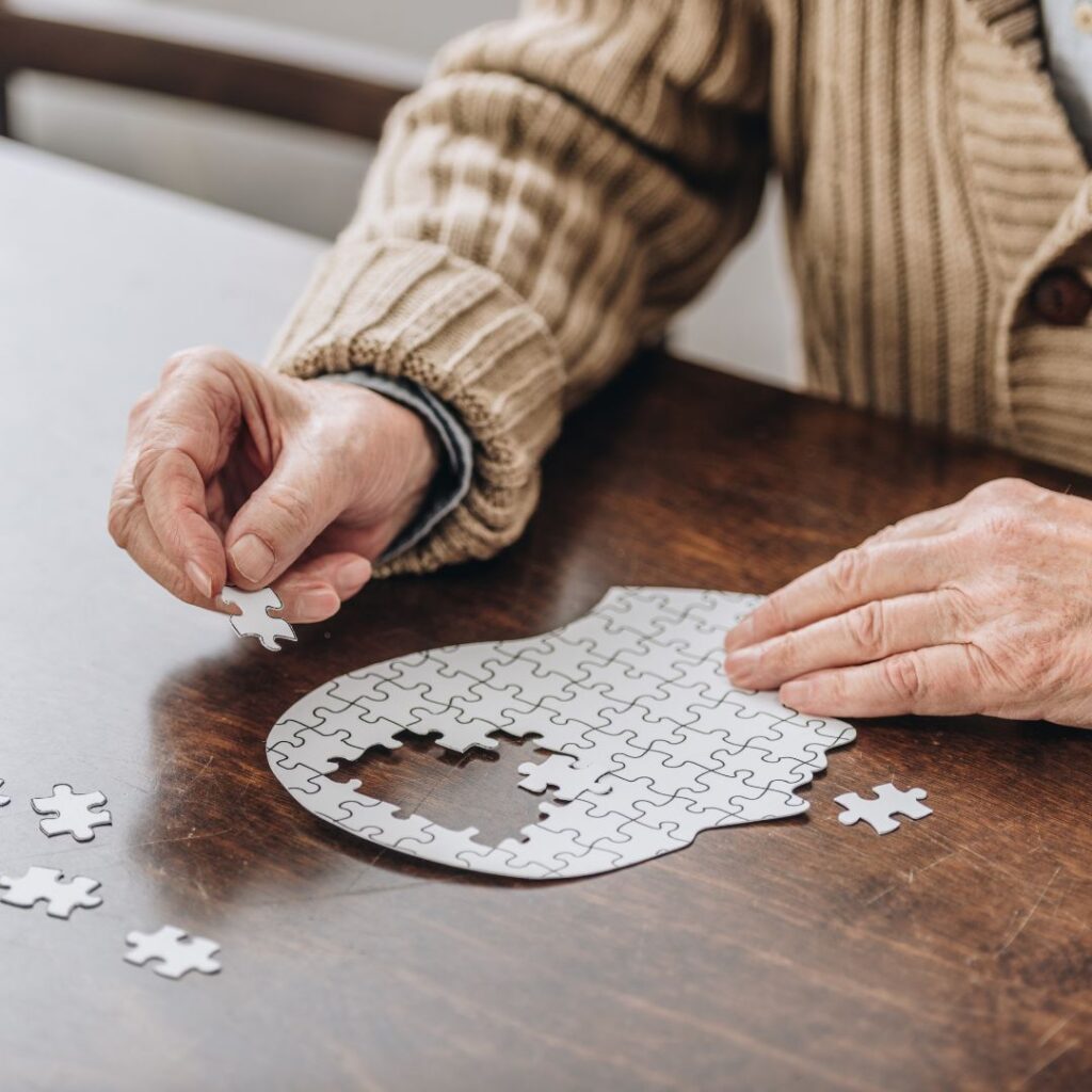 Old man with aphasia in speech, music and occupational therapy doing a jigsaw puzzle of a brain.