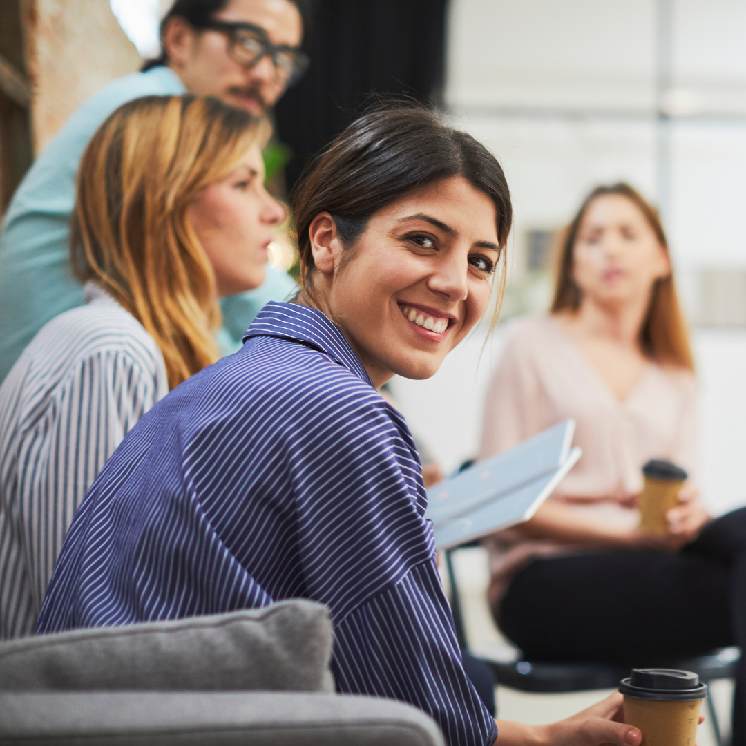 An adult man and three women sitting together - a woman is looking at the camera and smiling.