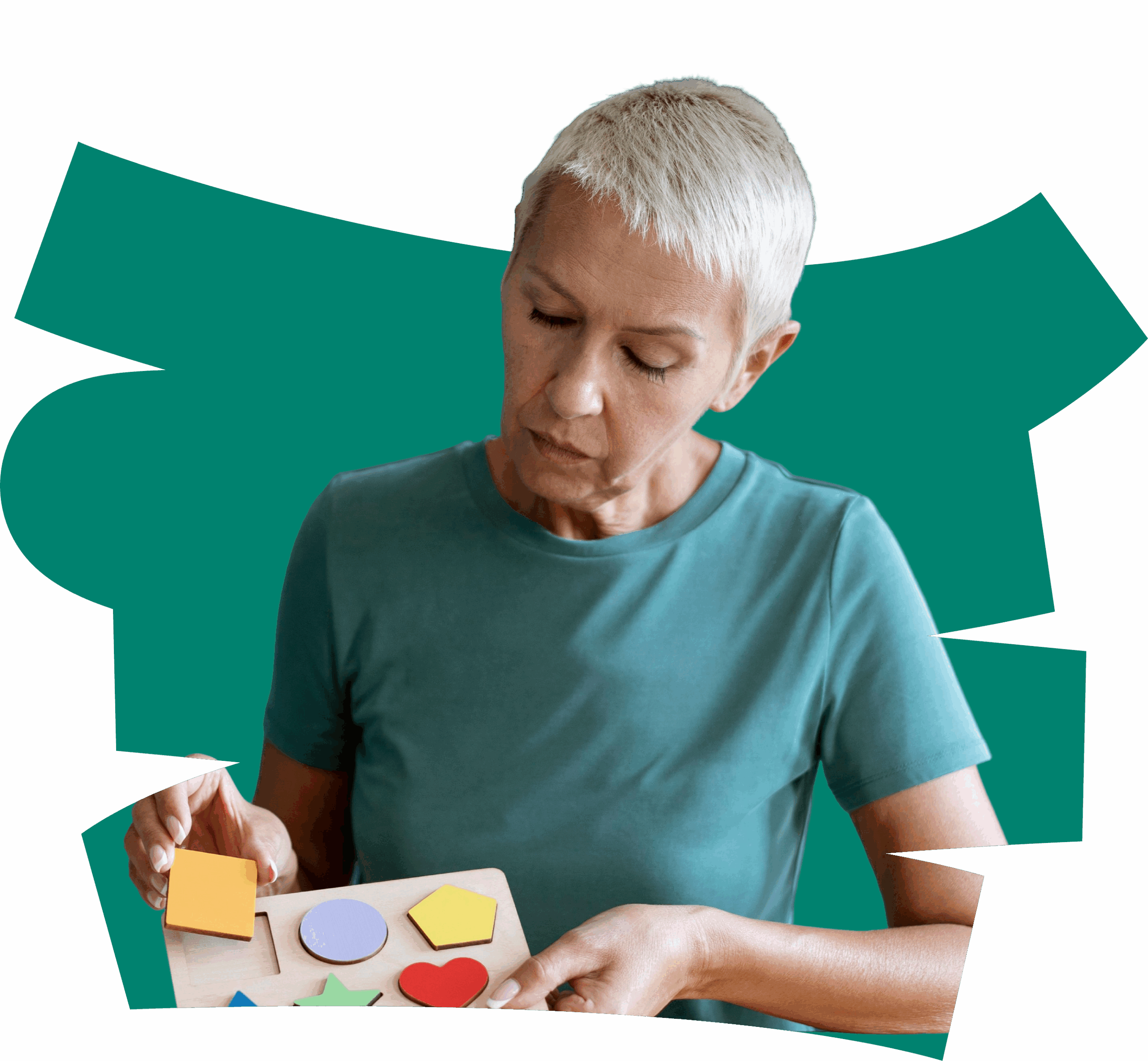 A woman with short grey hair, wearing a teal shirt, focuses on placing colourful geometric shapes into a wooden puzzle board—an activity often used in OT Gold Coast sessions. Abstract teal shapes form the background.