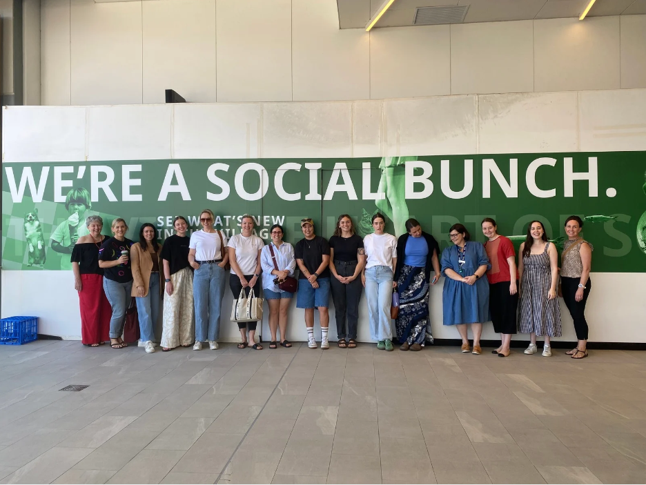 A group of women standing in a line under a sign that say 'We're a social bunch'.