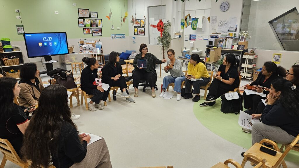 A group of early childhood educators sitting in a circle, some with ukuleles, engaging in professional development