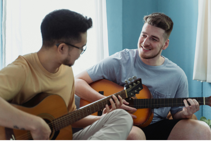Two men playing guitar together in music therapy recovery